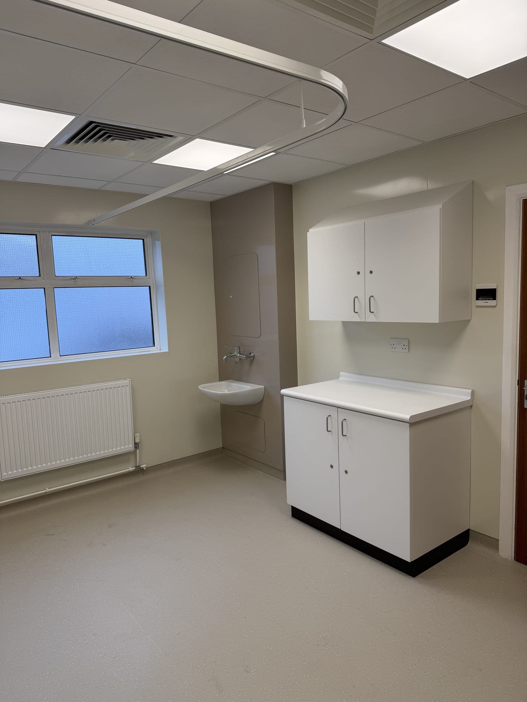 Refurbished clinical room with fitted units, radiator and window