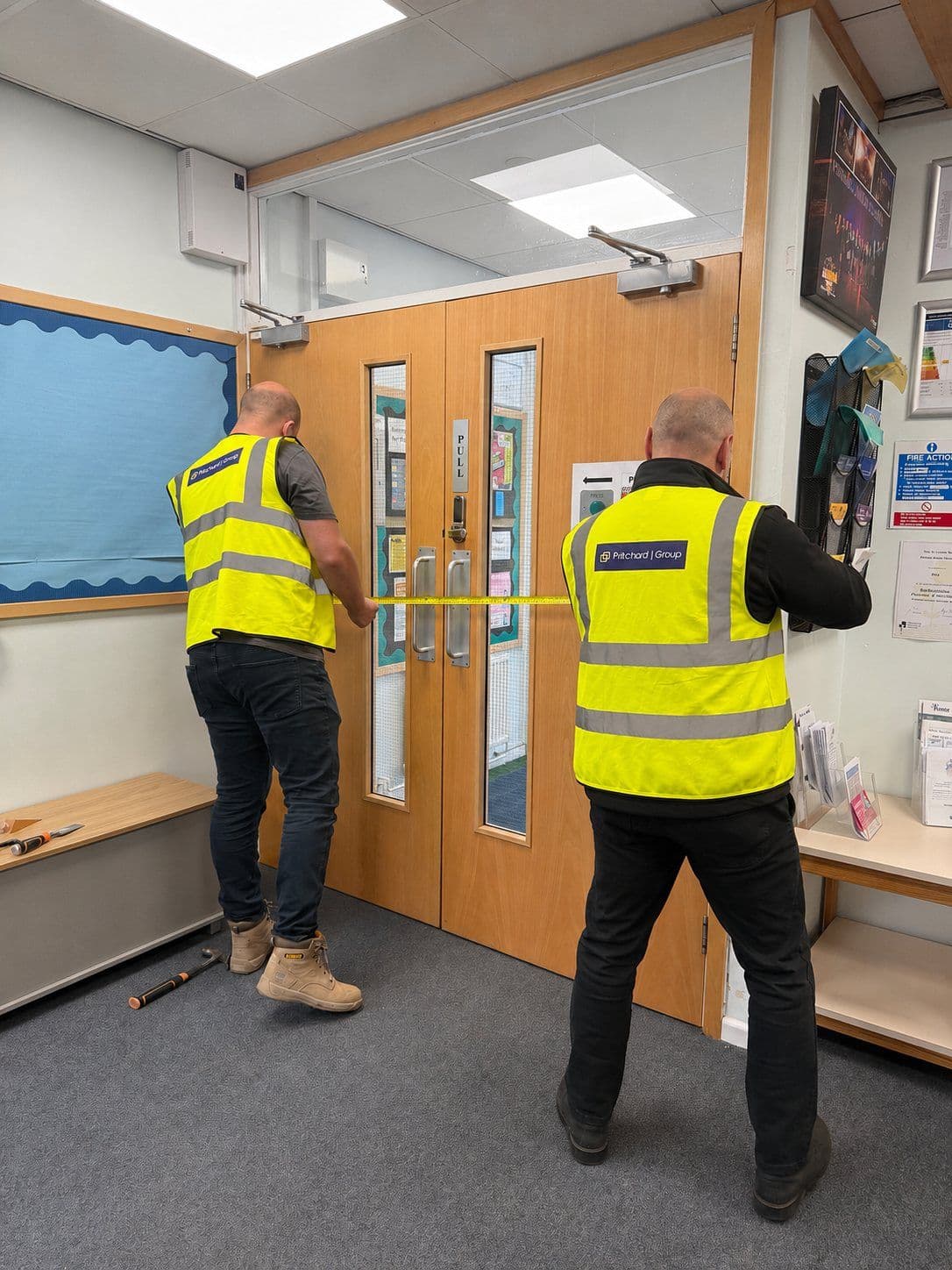 Two Pritchard Group operatives measuring a fire door opening in a school