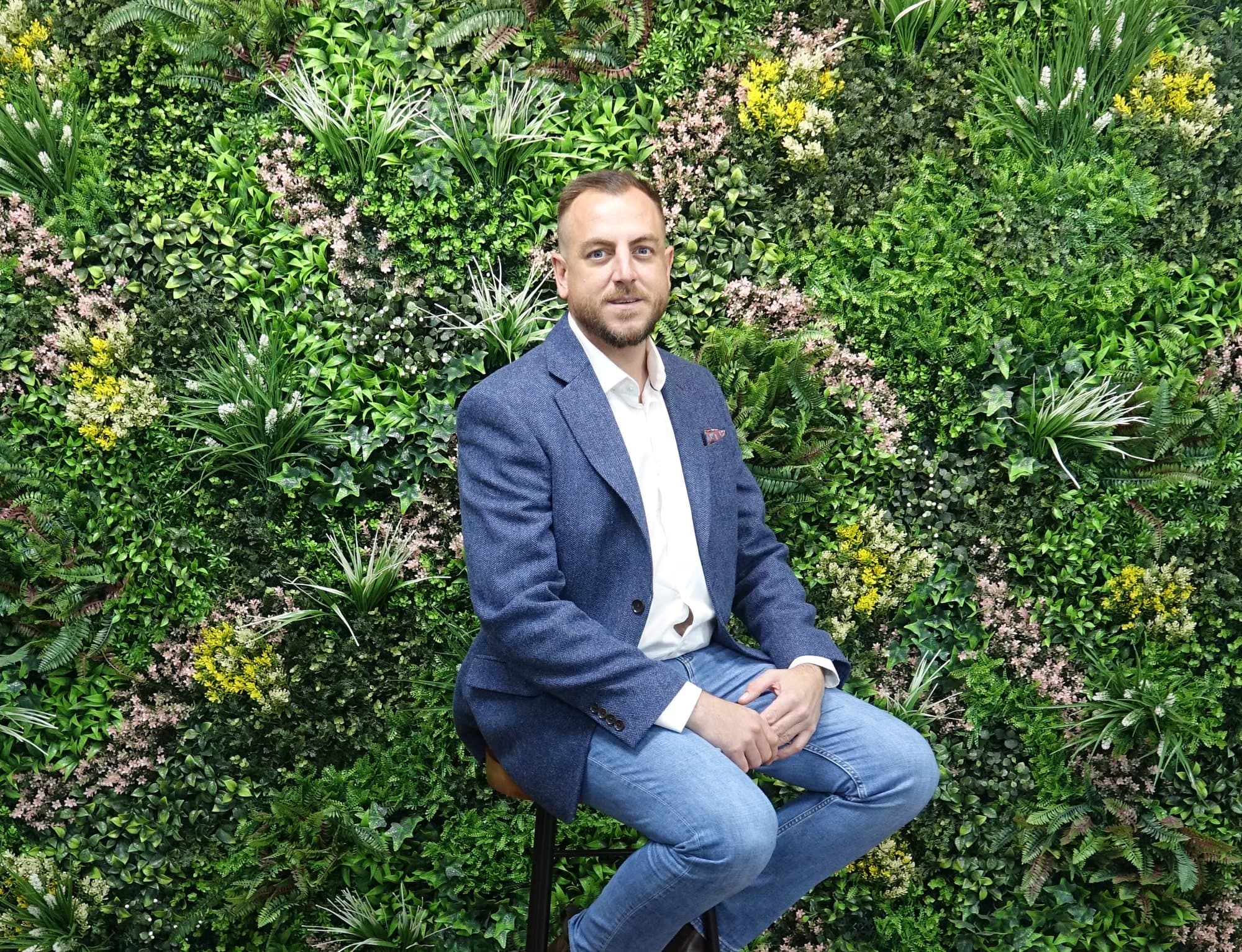 Shane Pritchard, founder of Pritchard Group, seated in front of a living plant wall