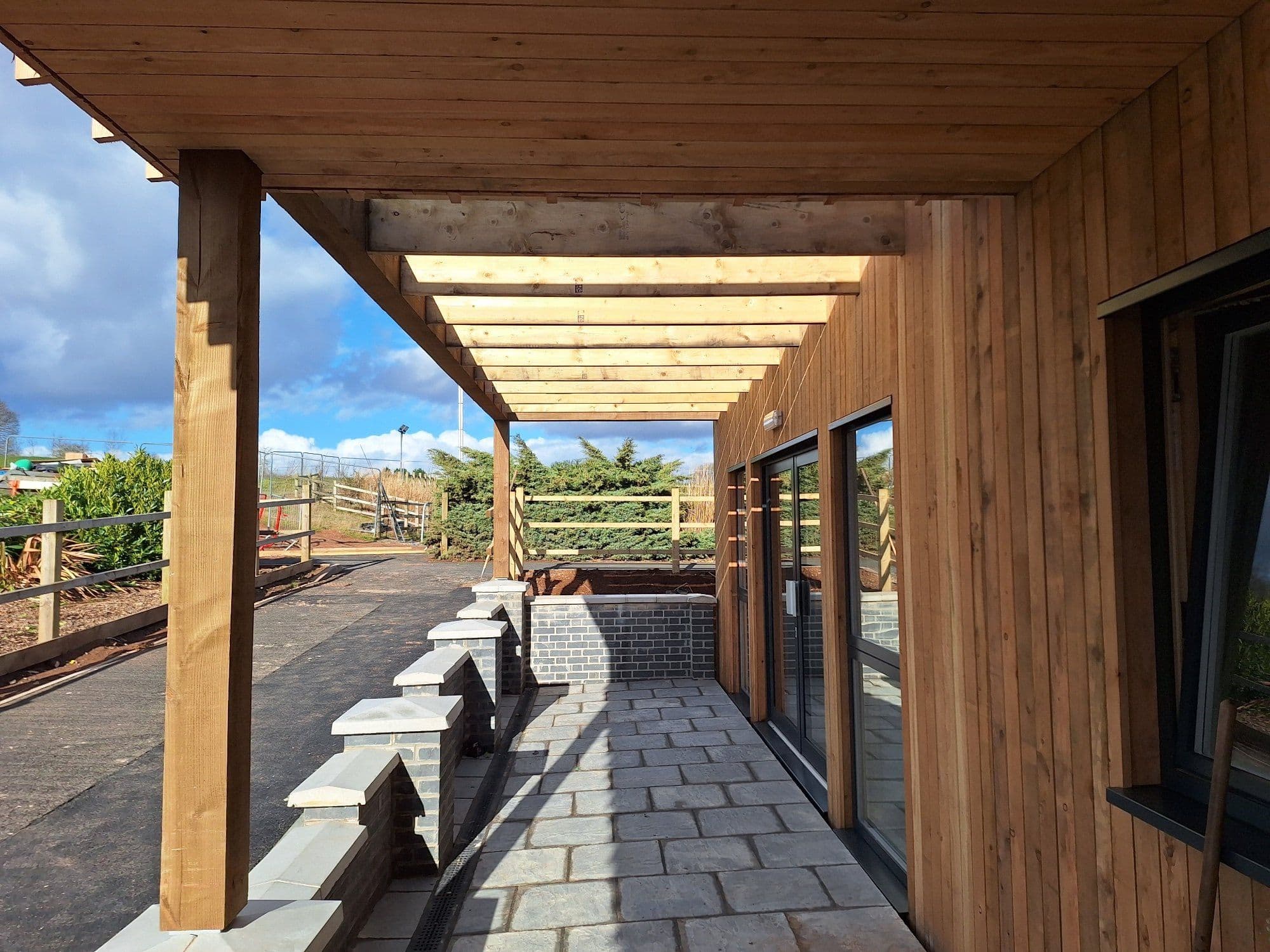 Covered walkway along the side of a timber-clad off-site school building